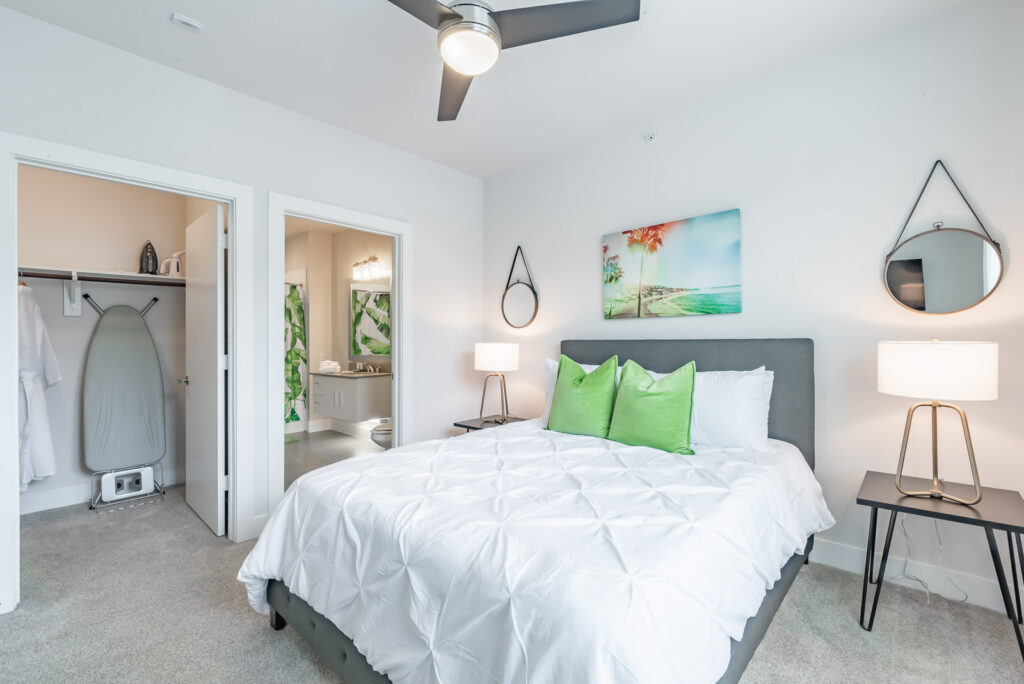 Inside of Stay Nixon rental unit bedroom with queen bed in the middleground flanked by two night tables and lamps